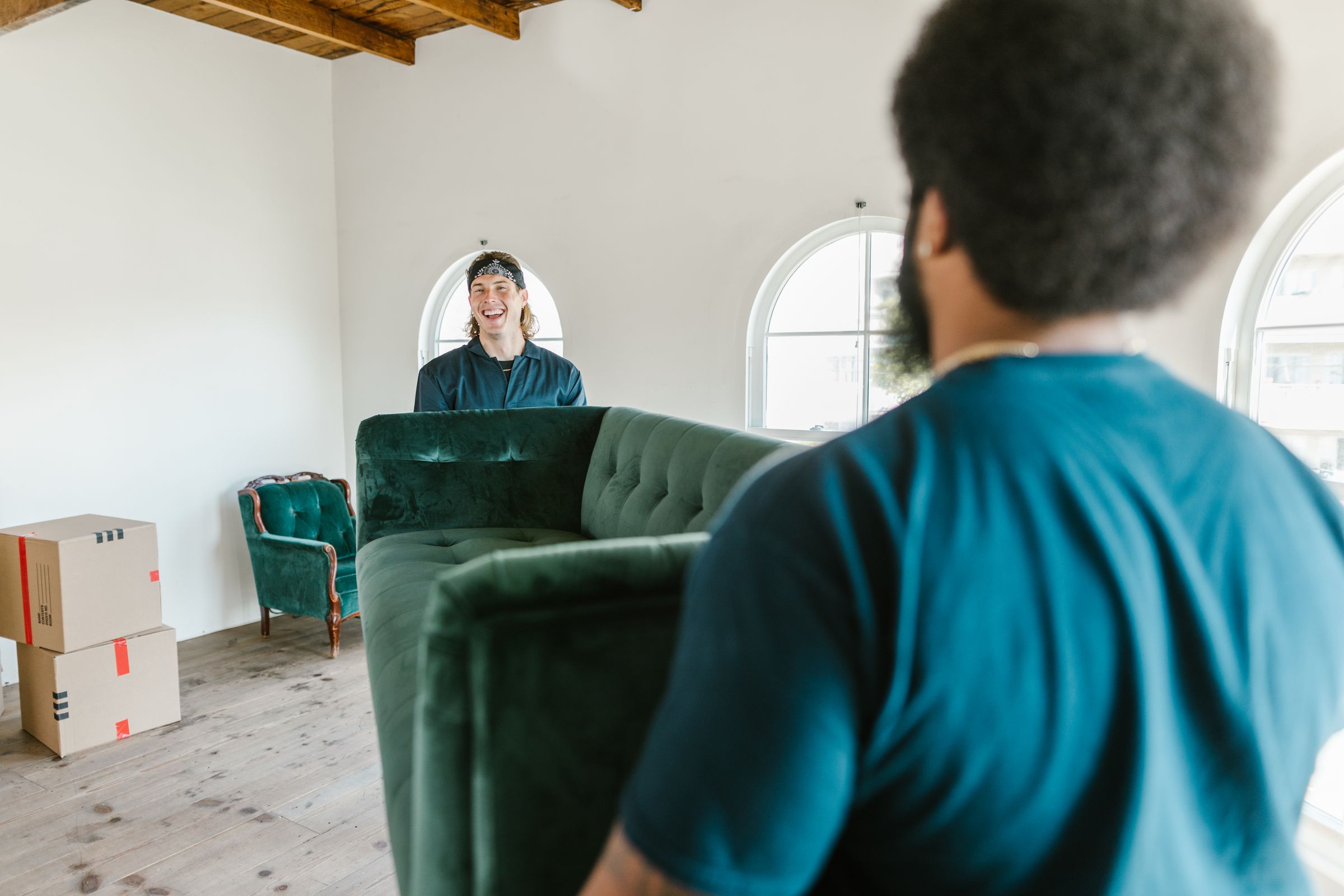 Two service professionals carrying a large couch from a room
